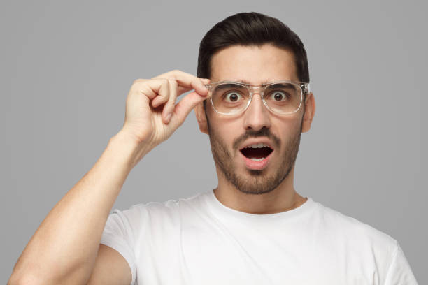 istock Surprised man shouting oh my god with open mouth, holding glasses 1391298405