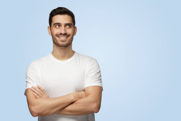 istock Attractive young optimistic dreamy man looks at camera standing with arms crossed 1391298459
