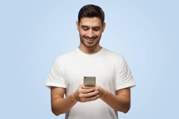 istock Attractive good-looking European man holds smartphone and smiles while looking at it 1391298506