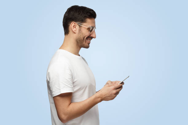 istock Attractive good-looking joyful man looks at smartphone while texting his friend 1391298513