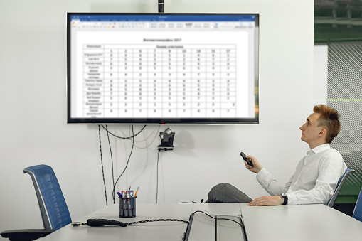 Portrait of young businessman indoors. Man showing screen on the display for template concept in the office of presentation