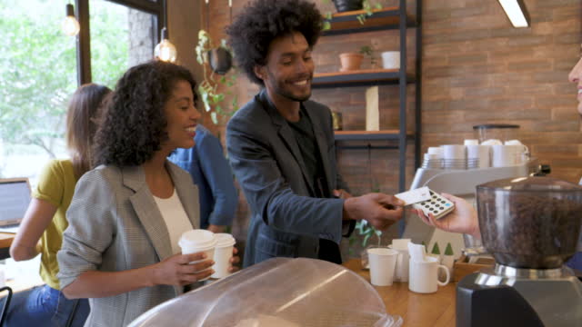 Brazilian customers making a contactless payment at a cafe using his credit card