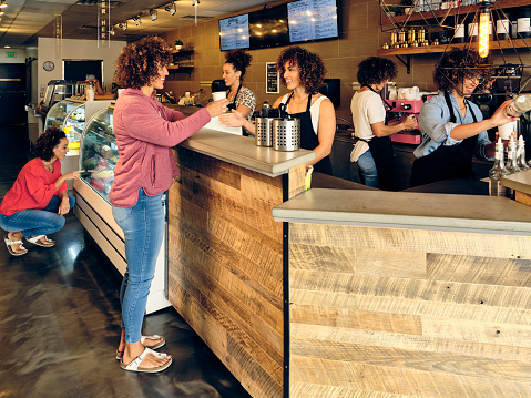 A coffee shop full of people, which are all the same woman.