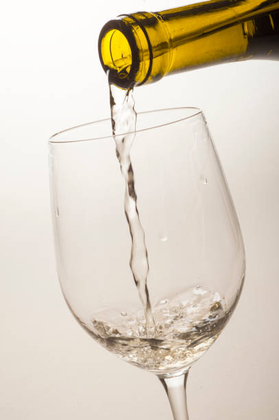 white wine is poured into a special glass on a light background in the studio close-up without a person stock photo