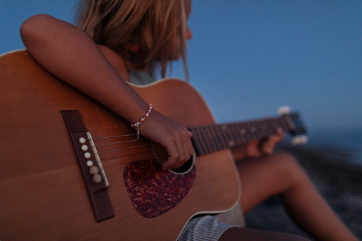 Close up photo of young blond boy playing guitar