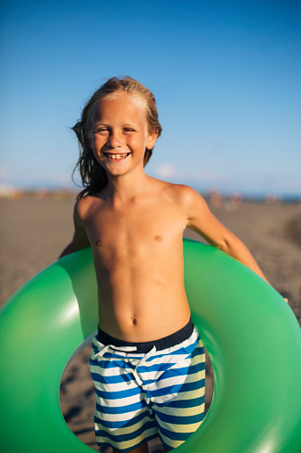 Kid carry green float at the beach
