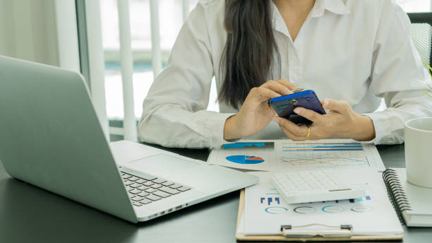 istock Businessman hand holding a smartphone, working on project statistics on devices. Presentation with graphs and an entrepreneur's accountant laptop analyzes financial data. show changes in the market 1391330886