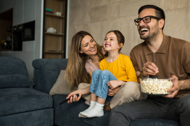 Happy young family watching tv together at home. stock photo