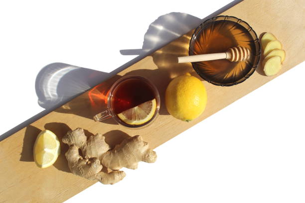 el jengibre y el limón se colocan en un plato blanco sobre una tabla de madera. medicamentos para el resfriado. - ginger tea cup cold and flu tea fotografías e imágenes de stock