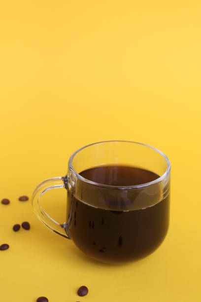 istock Glass cup with black coffee on yellow background 1391336553