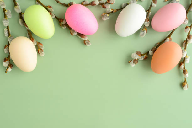 istock willow branches and easter eggs on a green background. beautiful fluffy sprigs of willow blooming and colored eggs on a green table, top view. Easter background 1391342766
