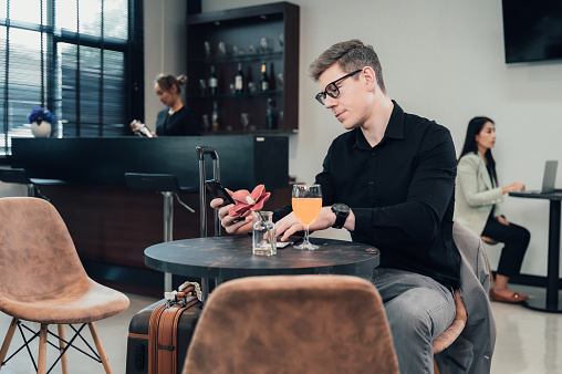 Young businessman uses his laptop to work while waiting for his flight in the lobby area. International travel by airline