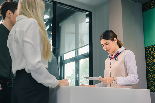 Attractive young businesswoman giving passport and ticket to staff at airport check in counter