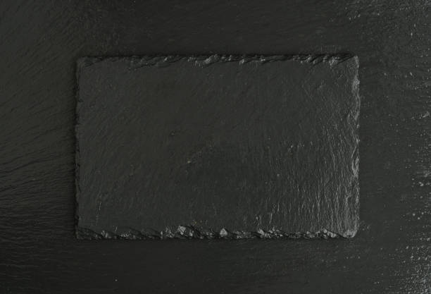 istock blank black stone slate plate on black slate background. Top view with copy space 1391347569