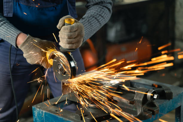 istock Locksmith in special clothes and goggles works in production. Metal processing with angle grinder. Sparks in metalworking 1391350968