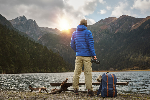 rear view of asian photographer looking at sunset over mountains