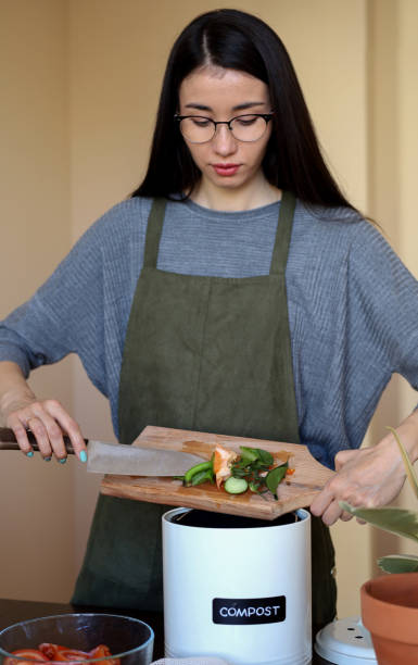 istock Young Asian vegan woman cleans vegetables and throws waste into a compost bin. Eco friendly person. 1391357266
