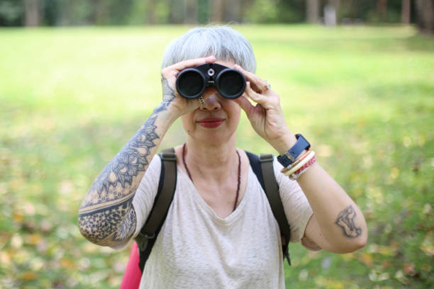 istock senior woman using binoculars to spot animals and things while hiking with backpacks and trekking in the forest. Concept of active lifestyle on retirement. 1391358841