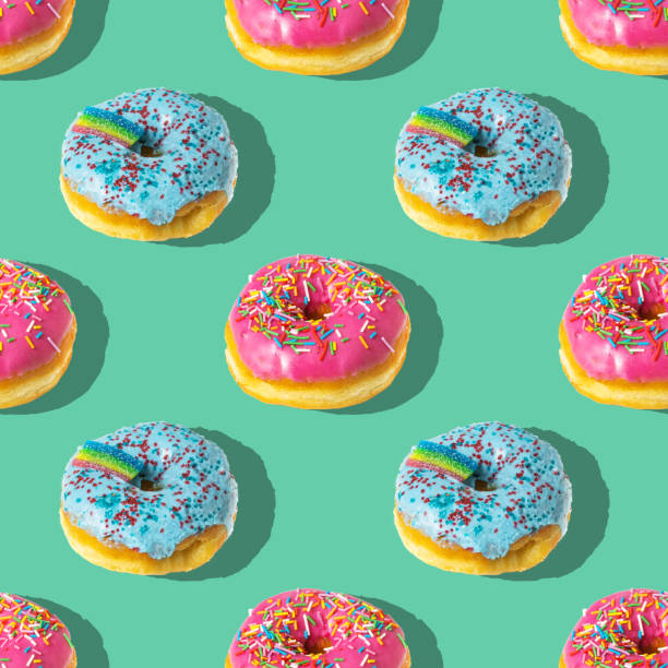 istock Repeating pattern of pink and blue rainbow donuts on a blue background 1391362329