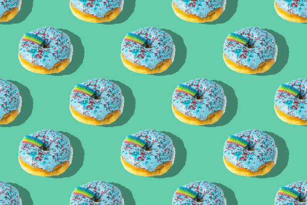 istock A repeating pattern of blue donuts with a rainbow on a green background. Flat lay 1391362868