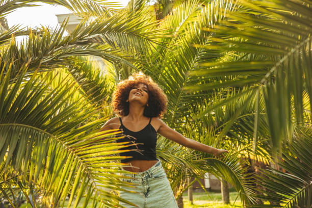 istock Pretty young afro woman among palm trees 1391363216