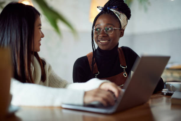 istock Two multicultural female students doing a school project on a laptop while drinking coffee in a cafeteria. 1391364717