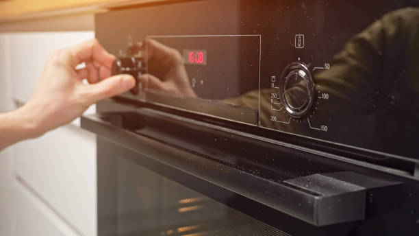 istock Man adjusts temperature and sets mode on oven in kitchen 1391369225