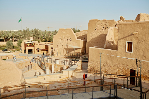 Wide angle view of traditional mud-brick architecture and preserved ruins at UNESCO World Heritage Site, desert oasis in background. Property release attached.