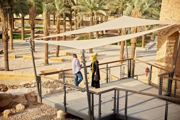 Elevated view of mid adult couple standing and talking as they explore At-Turaif, site of first Saudi capital and original home of royal family. Property release attached.