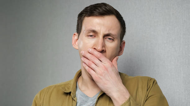 istock Young man yawns standing against grey wall 1391371092