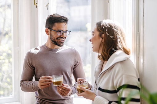 Coworkers standing next to a window and talking on a break a in co-working space