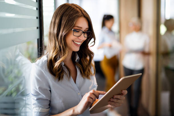 istock Attractive young businesswoman using a digital tablet while standing in front of windows in office 1391372118