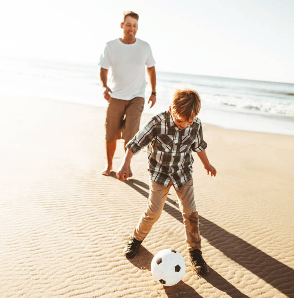 istock dad and son playing soccer on the beach 1391373825