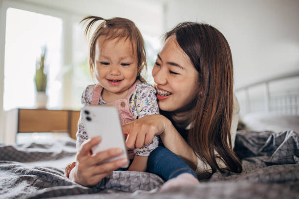 istock Mother and daughter lying on the bed and using smart phone 1391376307