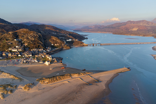 High angle aerial view of Barmouth Bay and Barmouth Bridge. The Bridge is a wooden railway viaduct across the estuary of the Afon Mawddach. It is 820 metres long and carries the Cambrian Main Line. It is the longest timber viaduct in Wales and one of the oldest in regular use in Britain.