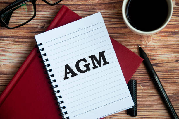 istock Annual general meeting text on notepad with office setting background. Meeting concept 1391378585