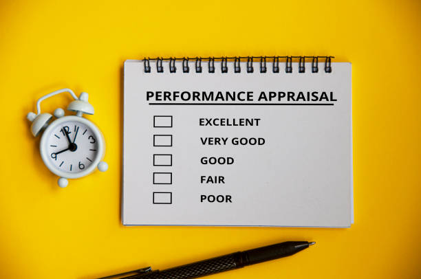 istock Performance appraisal checklist on notepad with pen and alarm clock on yellow cover background. Performance review concept 1391378693