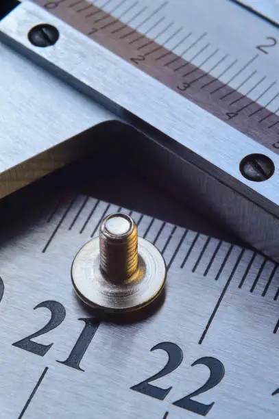 caliper and nuts with a bolt, a metalwork measuring tool lies on the background of metal rulers. close-up