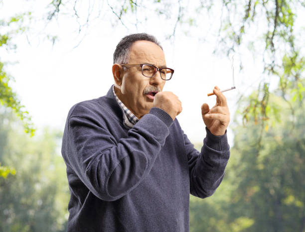 mature man smoking and coughing outdoors - nicotine healthcare and medicine smoking issues lifestyles imagens e fotografias de stock