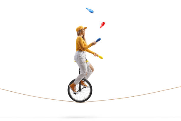 Young female riding a unicycle on a tightrope and juggling Young female riding a unicycle on a tightrope and juggling isolated on white background political joke stock pictures, royalty-free photos & images