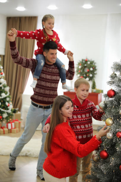 istock Mother and son decorating Christmas tree while father playing with daughter at home 1391392507