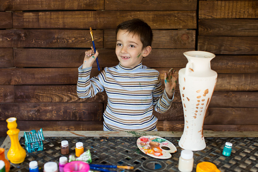 a child paints a vase in the garage