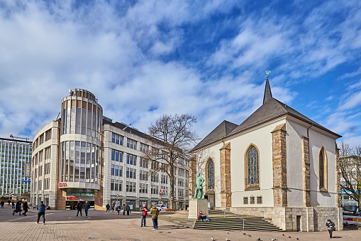 Essen, Germany - February 24, 2022: Pedestrians on Kennedyplatz in Essen. on the right the small market church.