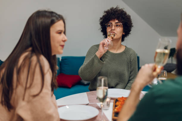 istock Group of friends enjoying dinner while sitting at the kitchen table together 1391399077