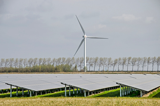 Middelharnis, The Netherlands, March 30, 2022: field of solar panels and a wind turbine in the polder landscape of the island of Flakkee