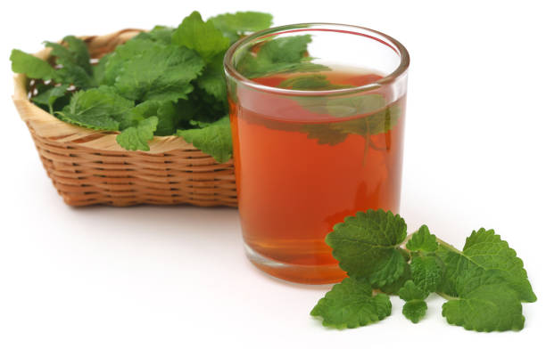 Lemon balm leaves with herbal tea in a transparent glass over white background