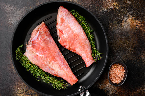 pescado de perca roja del océano de mar fresco, en sartén de hierro fundido, sobre un viejo fondo de mesa rústica oscura, vista superior plana lay - rockfish fotografías e imágenes de stock