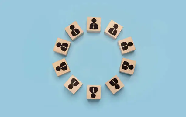 round table, business meeting concept. businessmen icons on wooden cubes arranged in circle on blue background. discussion of important issues, round table talks