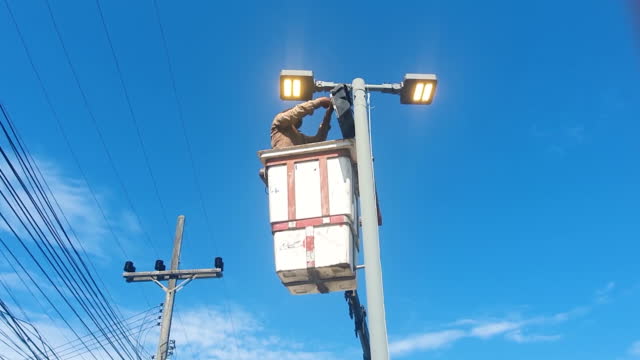 Powerline worker changing LED street lamp