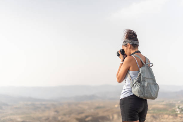 istock Anonymous woman with backpack taking photo in mountains 1391403958